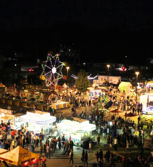 ferris wheel a night surrounding by rides and people