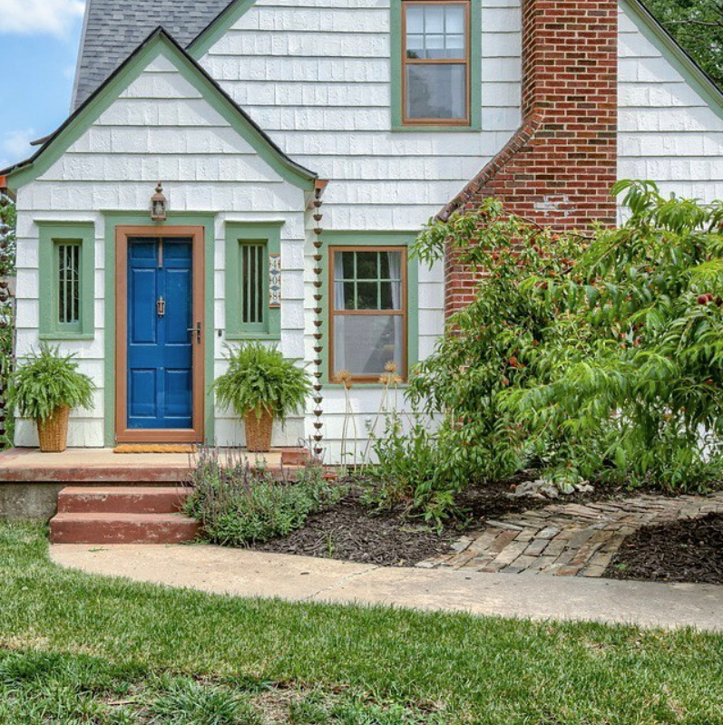adorable tudor home with blue front door, curved sidewalk